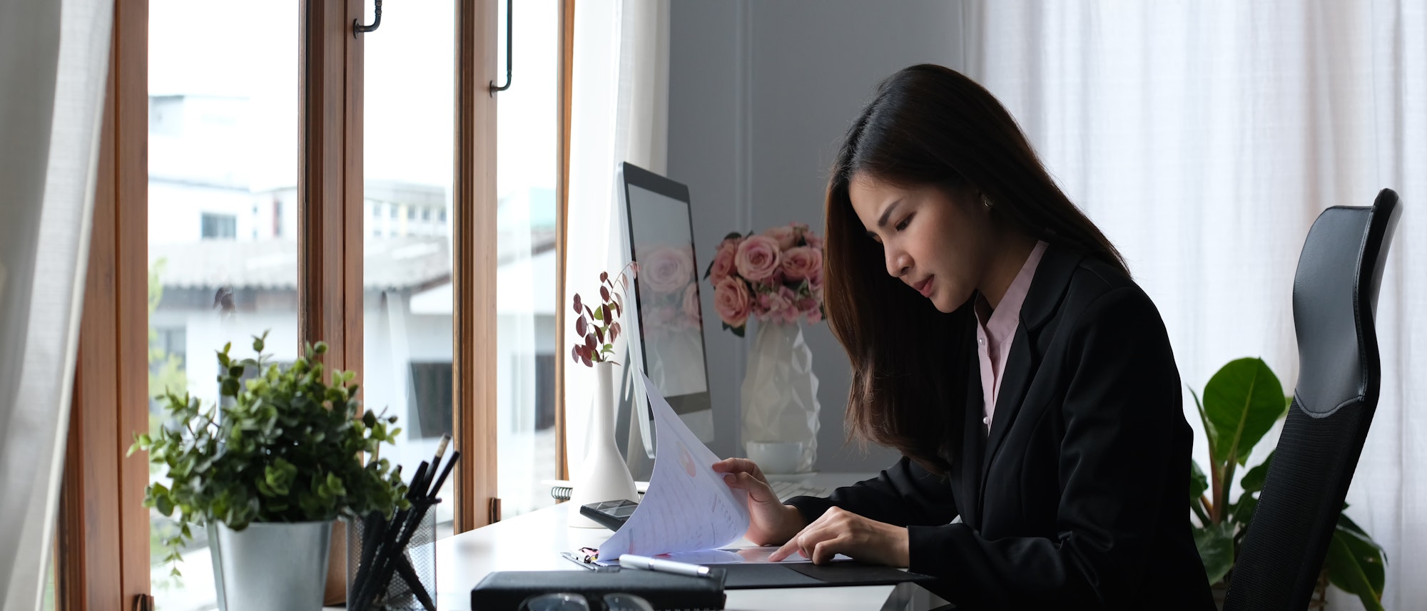 Serious female accountant comparing corporate income for previous year.